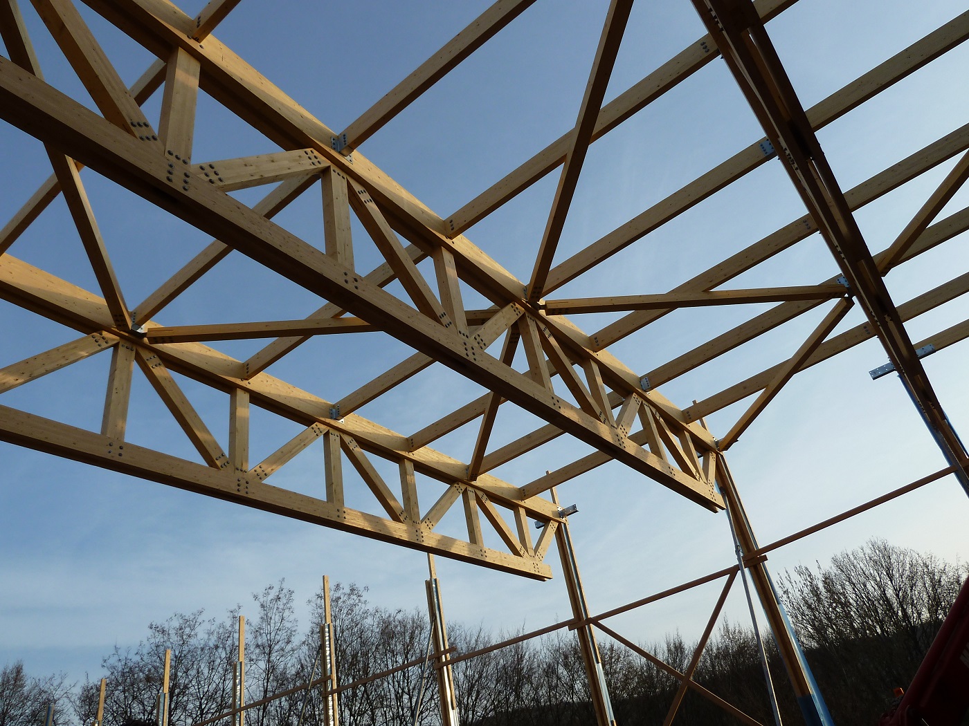 Construction d’un centre sportif charpente poutres treillis en bois lamellé-collé.
